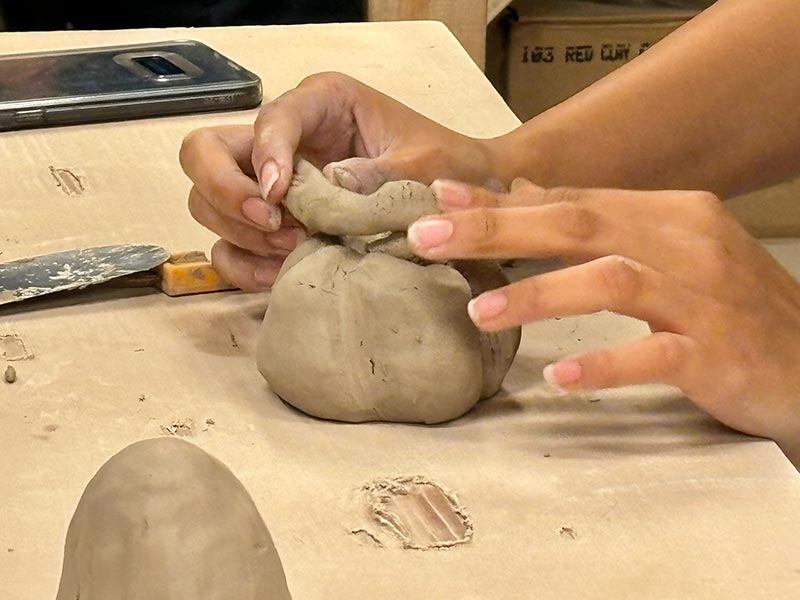 photo of hands sculpting a clay pumpkin